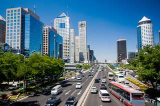 Geschäftsbezirk von Peking Blick in eine mit Autos befahrene Straße mit Hochhäusern vor blauem Himmel in einem Geschäftsbezirk in Peking.